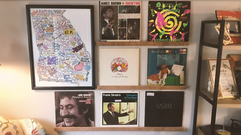 Three record shelves with records on them on a living room wall