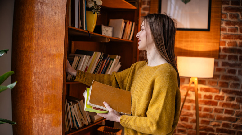 A young woman browses for books at an old bookshelf