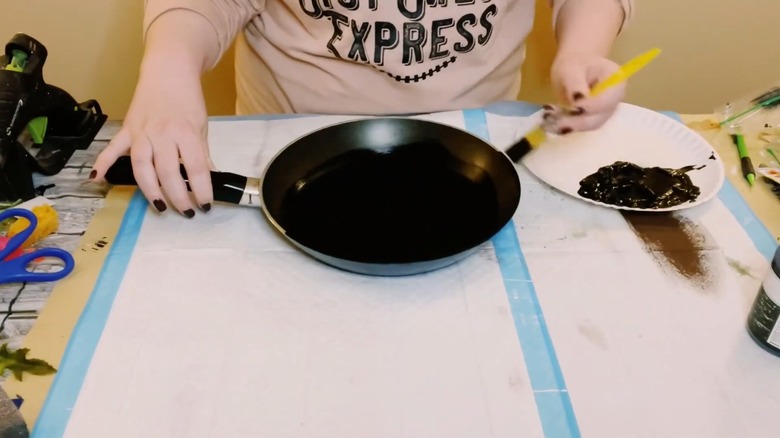 Woman painting an old pan black