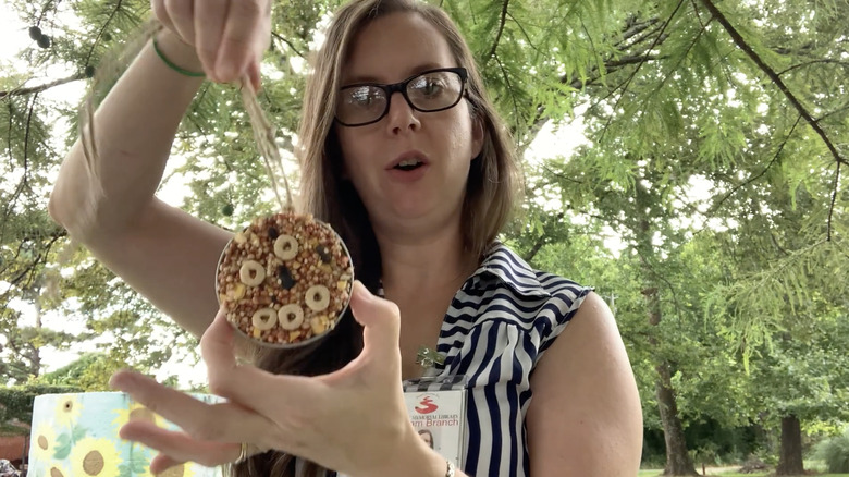 person holding Mason jar lid bird feeder
