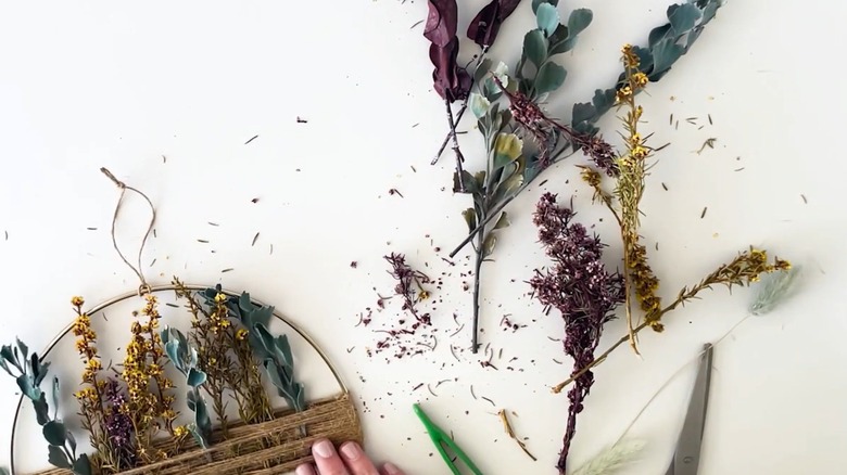 Messy and shedding dried flowers on crafter's white table for DIY project