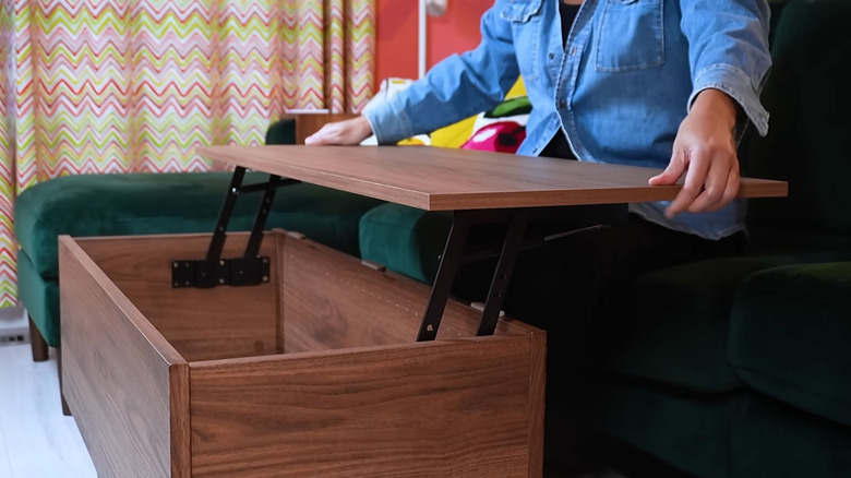 A person opens a lift-top coffee table