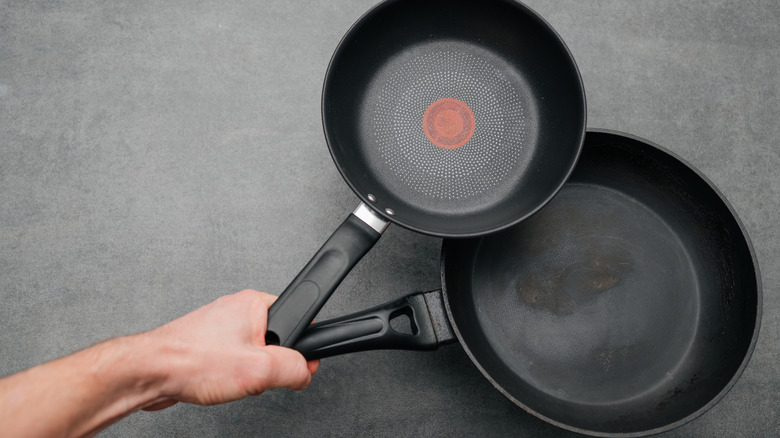 Hand holding two frying pans