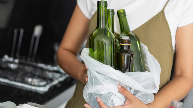person holding bag of empty glass bottles