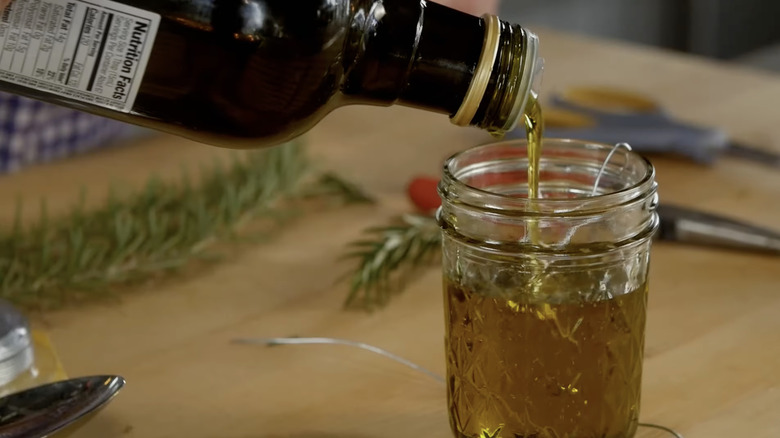 Olive oil pouring from a bottle into a Mason jar