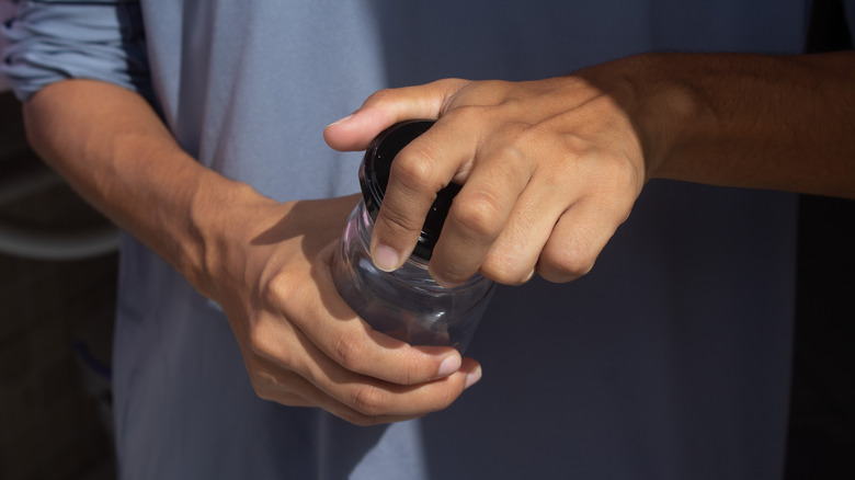A person opening an empty Mason jar