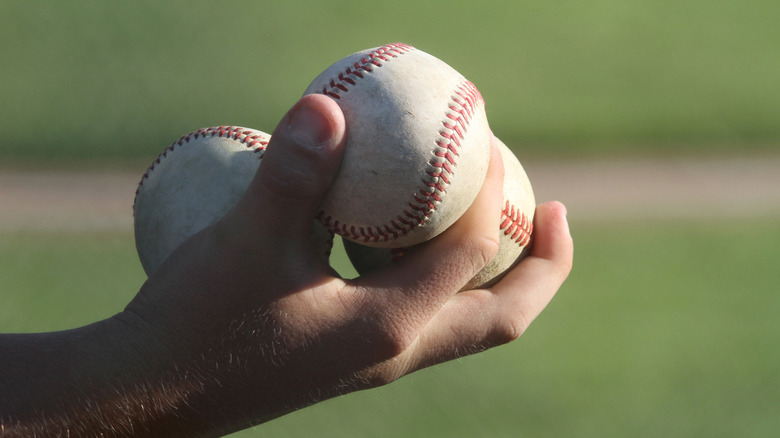 Person holding three baseballs with their hand