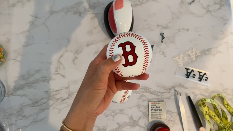 Person preparing a baseball for a craft project