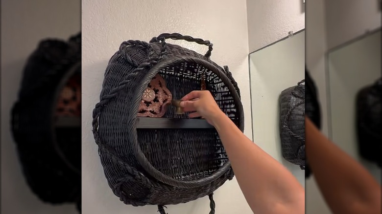 Creator putting items on a shelf in a basket hanging on a wall