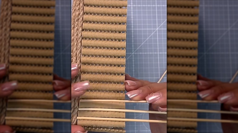 Woman making basket from piece of bath mat and dowels
