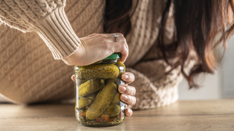 A woman opening a pickle jar.