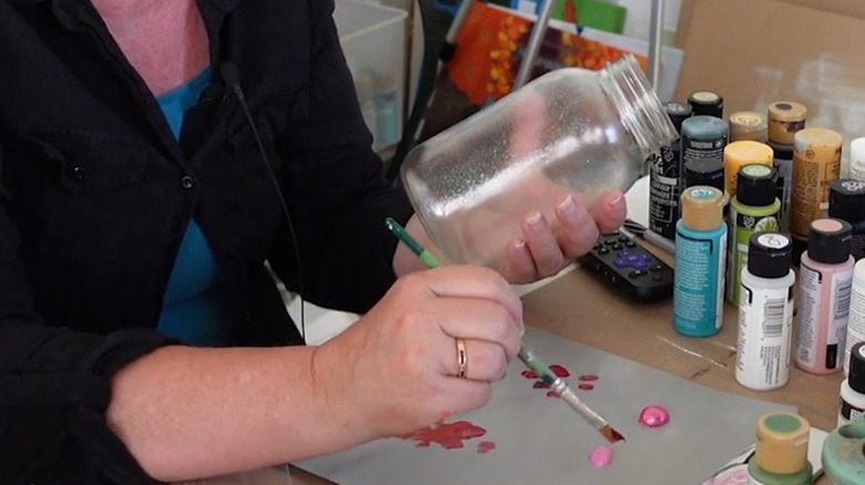 Person painting an old Mason jar