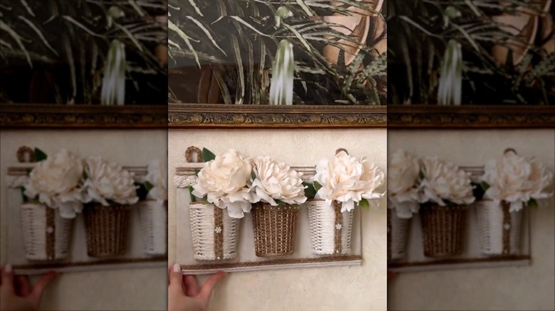 Three faux-baskets full of flowers mounted on a board