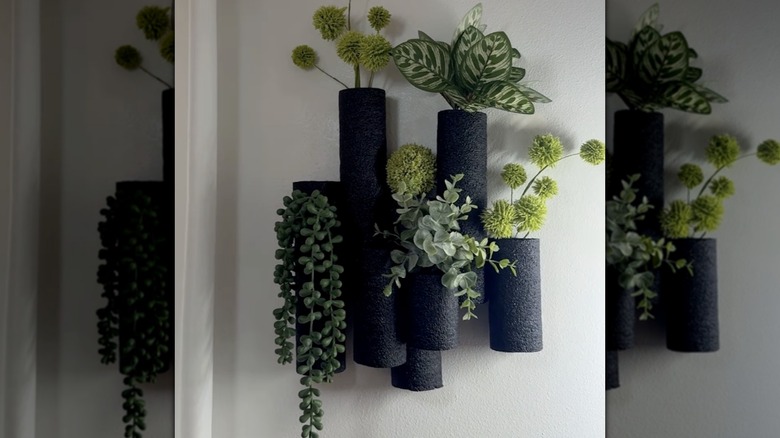 Black pool noodles transformed into a wall-mounted vase with faux greenery