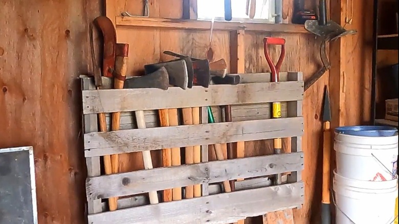 A wood pallet mounted to a garage wall with tools inside