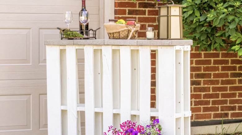 A mini bar made out of pallets painted white and pavers