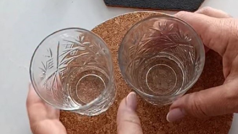 Woman holding drinking glasses on top of a cork board