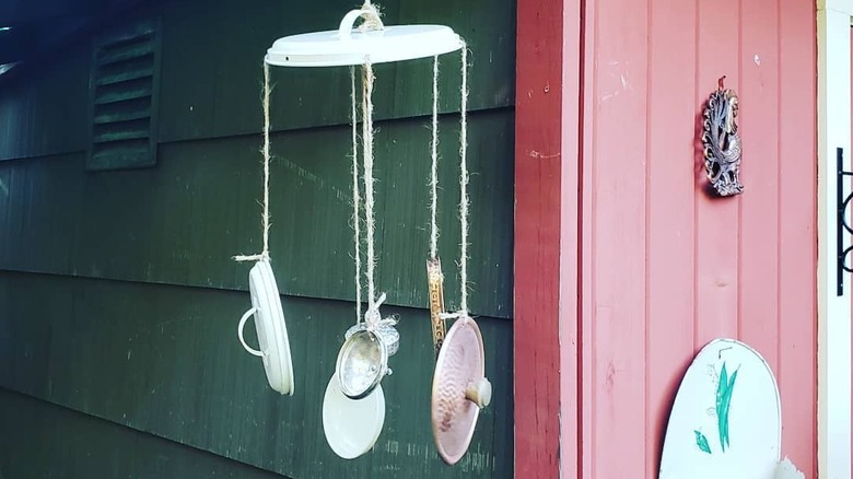 DIY wind chimes made from pan lids hanging near a shed