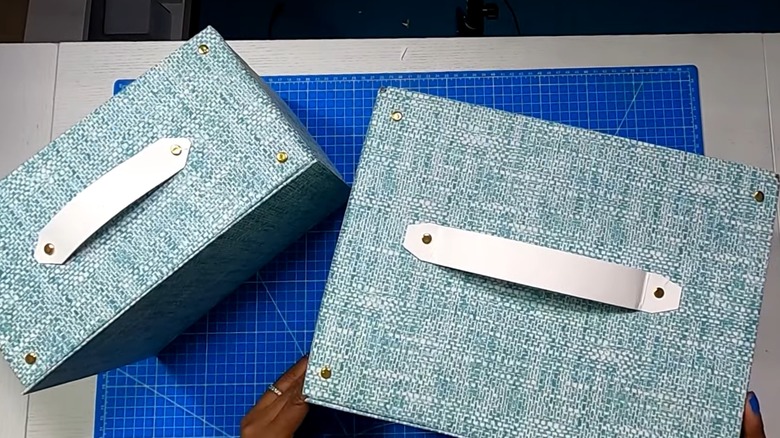 Pair of shipping boxes wrapped in blue paper with DIY white handles for storage