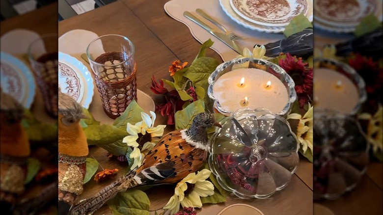 A lit pumpkin candle as a centerpiece on a dining table