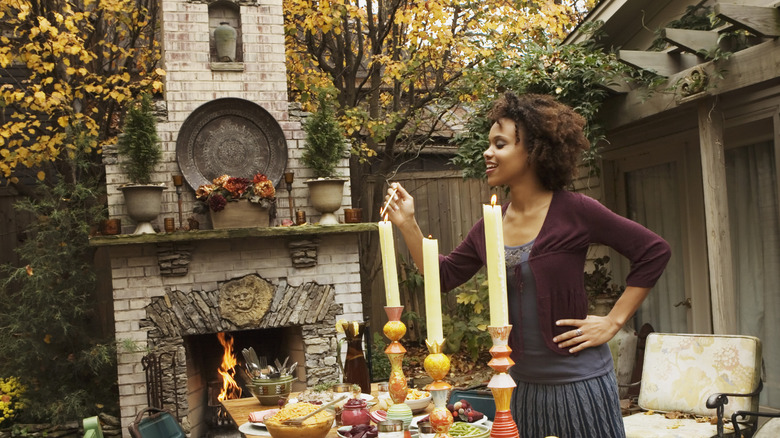 A woman lights candles on a fall themed tablescape