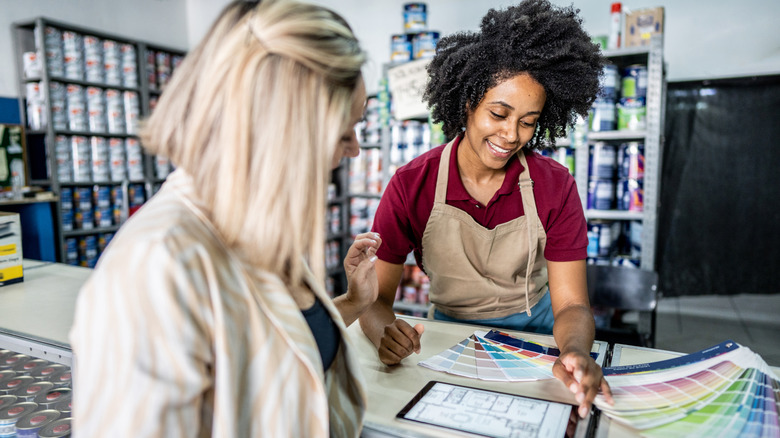 A salesperson shows a customer paint samples in a store