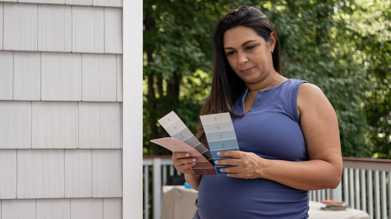 A woman holds paint swatches on her porch