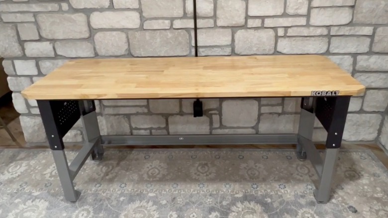 Empty Kobalt Adjustable Height Work Bench in front of stone wall