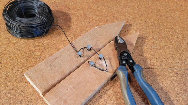 Joining two garden edging boards with bailing wire, allowing slack for future adjustment