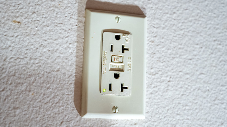 Electrical outlet installed upside down on white wall
