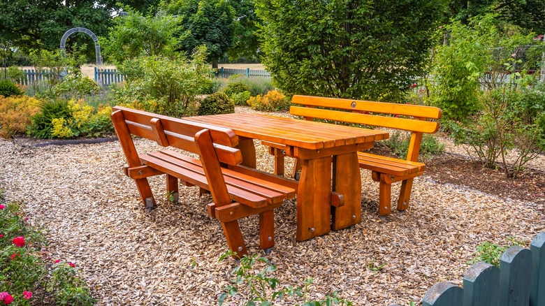 Wooden table and chairs on a mulch patio in a well landscaped yard