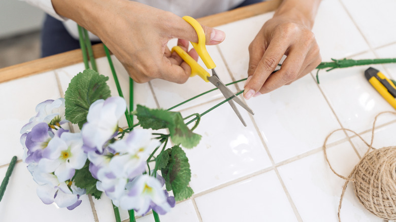 Woman cutting faux flower stems with scissors