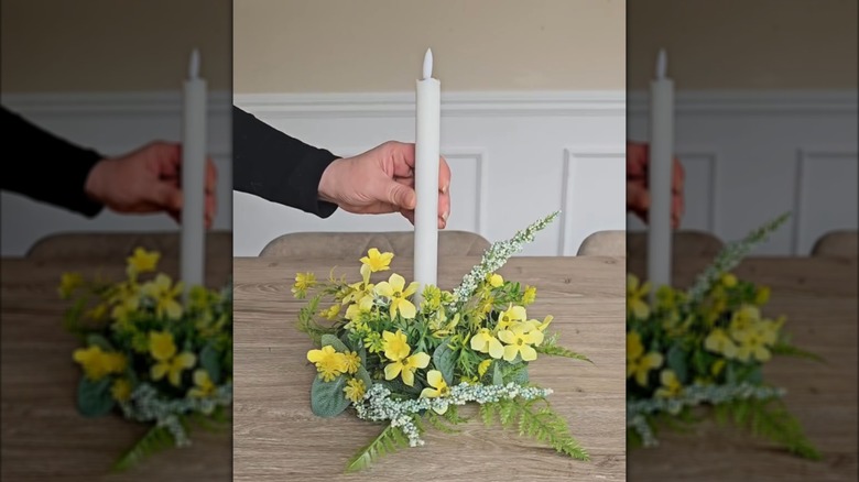 Woman setting taper candle into artificial foliage foam candle holder