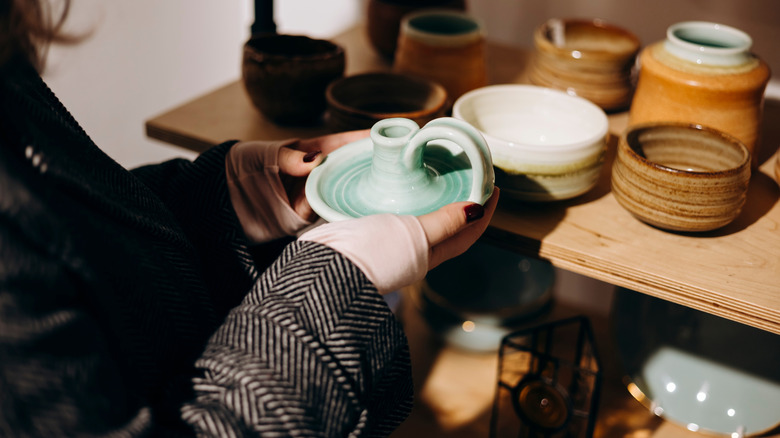 Woman picking up old candle holder at store