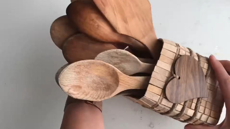 Creator holding the milk jug utensil holder with wood utensils in it