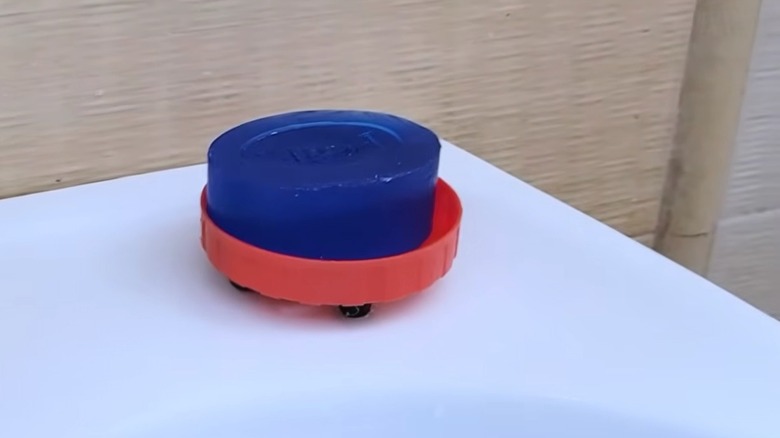 A plastic lid soap dish sitting on the edge of a sink