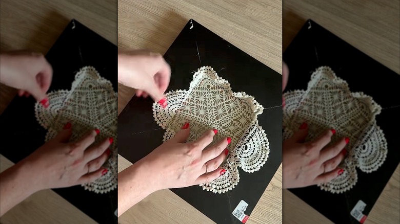 Hands laying doily over picture frame