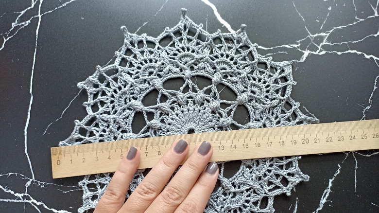hand measuring fabric doily
