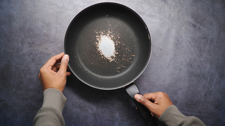 A person lays an old frying pan on a table
