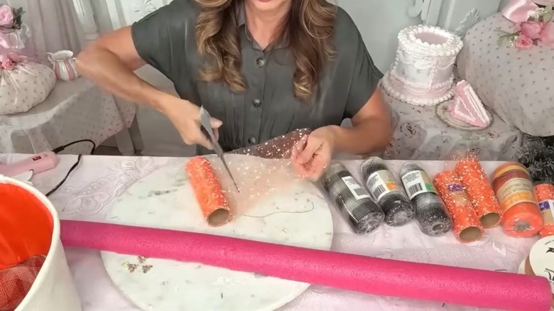 A woman cuts through crafting mesh in an ornate room