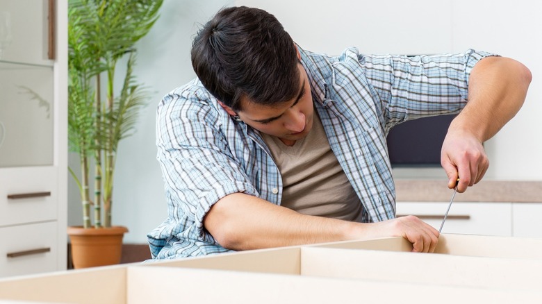 Man assembling a bookcase for a home office.