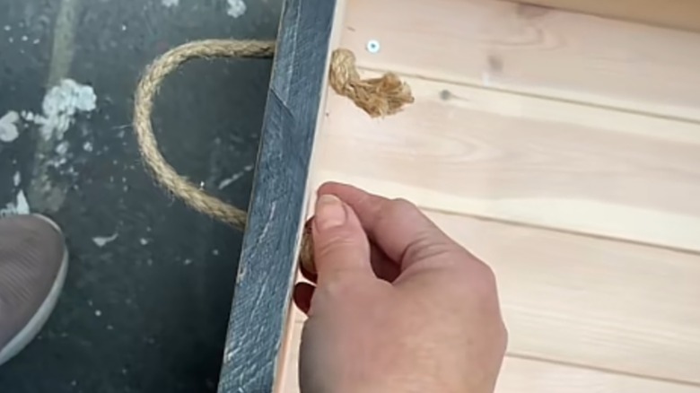 Person putting a rope handle on a wooden box