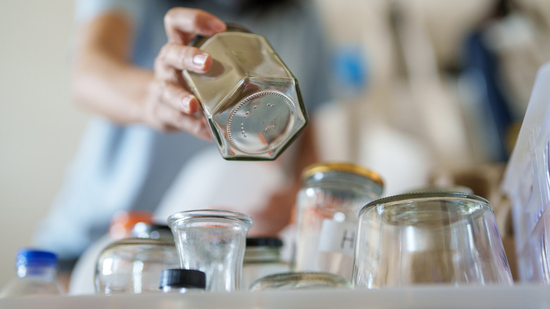 Person picking a glass jar out of a box of jars