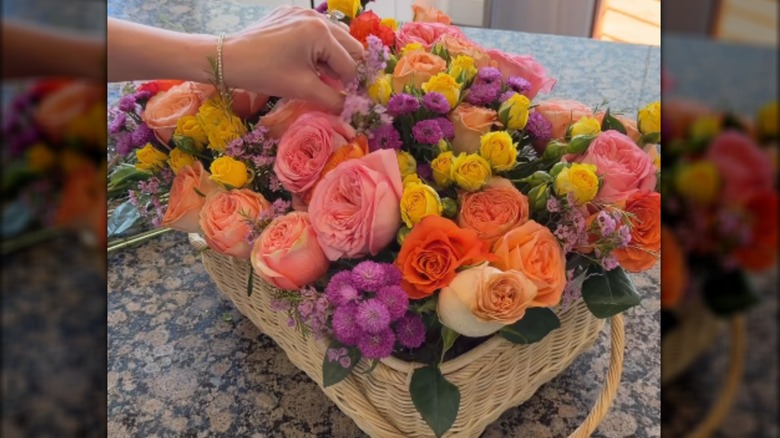 Creator putting the final touches on a floral arrangement inside a basket