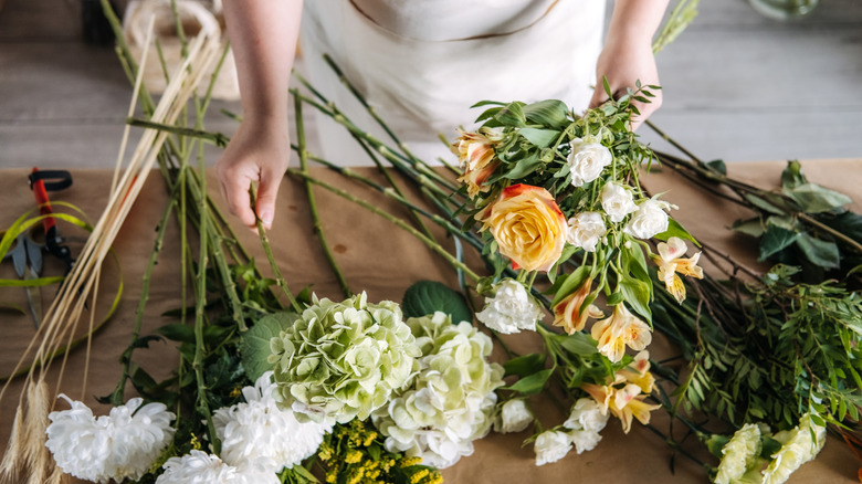 Person picking up different flower stems to start a floral arrangement