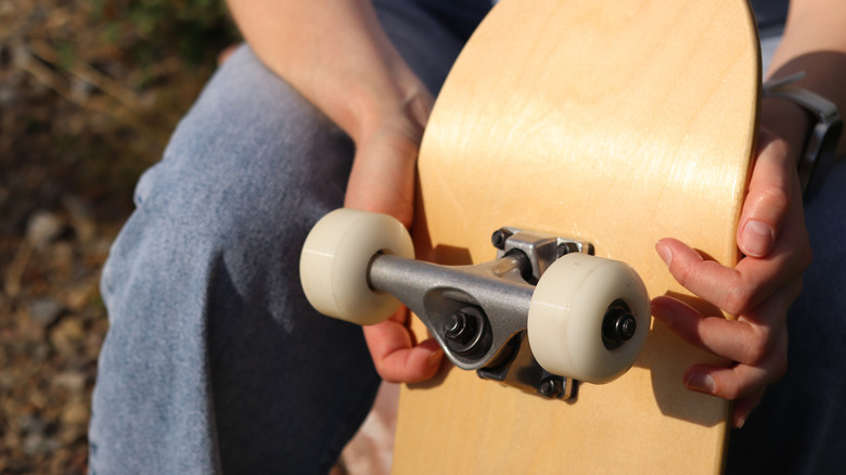 Person holding up a plain wooden skateboard