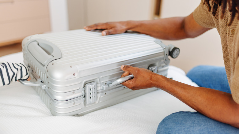 Woman holding a suitcase on the bed