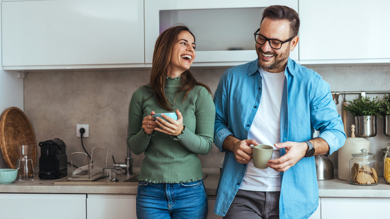 A couple in kitchen together with cluttered counter in background