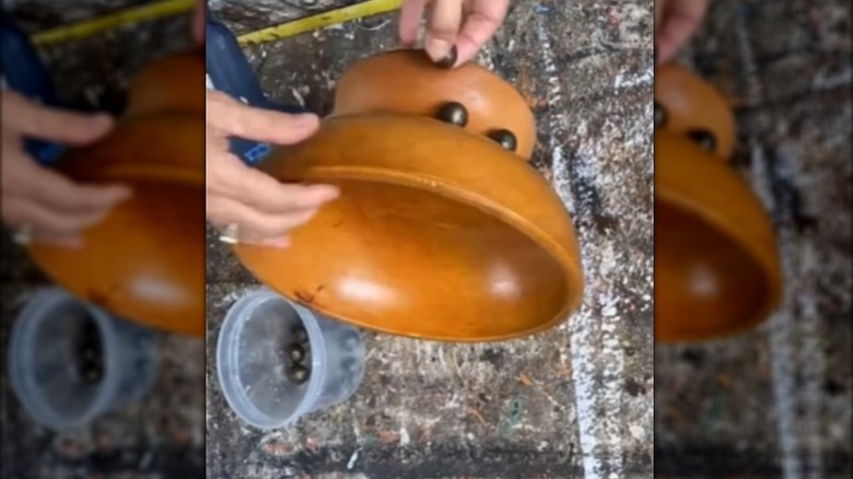 Creator adding wood beads on the side of a wooden bowl display