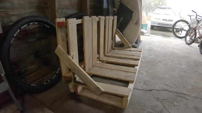 An L-shaped bike rack made from wood pallets and leftover 2x4s in a garage.